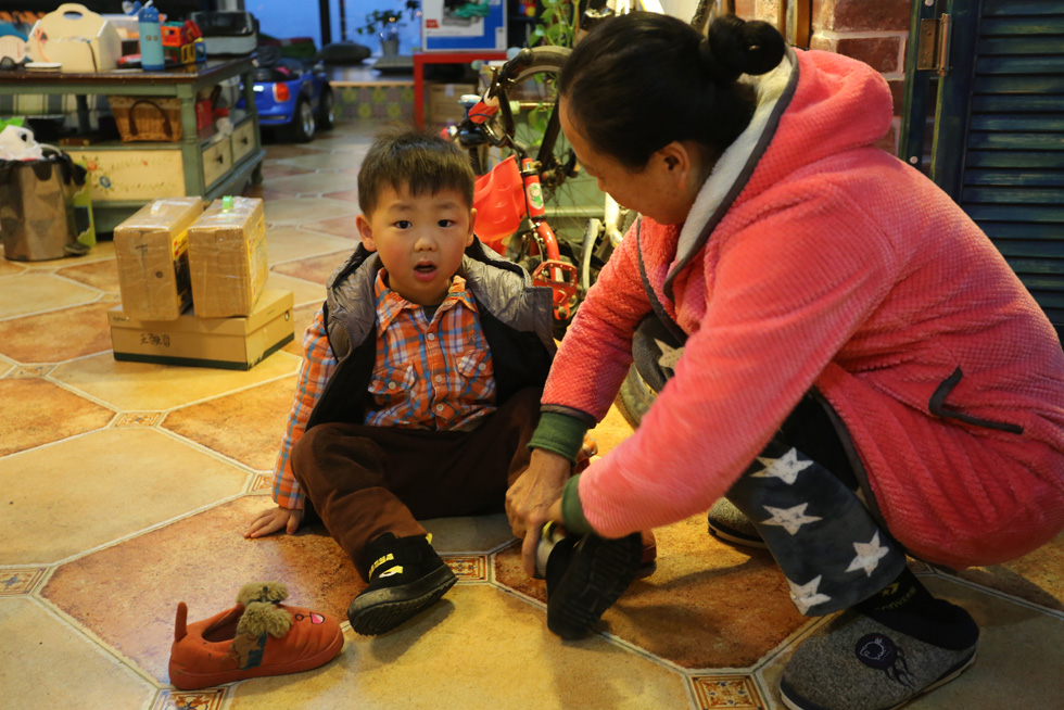 醒来还有点迷迷糊糊的，外婆帮着王骏哲小朋友穿鞋子。